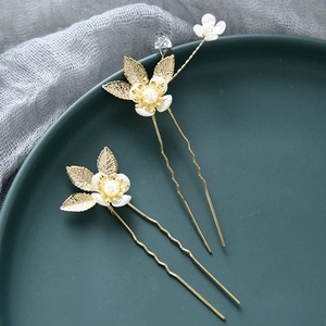 Détail d'épingles à cheveux de mariée avec fleurs en nacre, perles et feuilles d'or