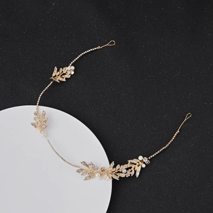 Golden bridal hair vine with leaves, pearls and crystals on a white display base