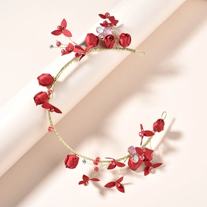 Détail de roses en satin rouge et perles de strass sur un bandeau floral doré
