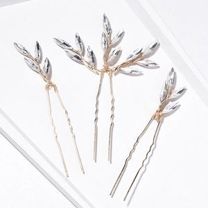Detail of three-piece golden bridal hair pins featuring leaf designs and crystal marquise stones