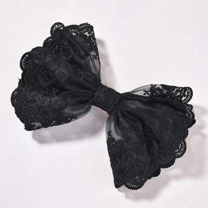 Détail de l'élégante pince à cheveux en dentelle noire avec broderie florale raffinée