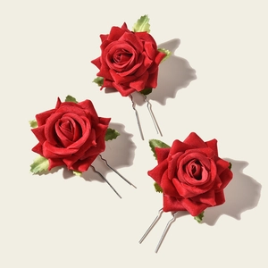 Detailed view of red fabric rose hair pins with green leaves and silver U-shaped pins