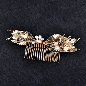 Detailed macro view of golden alloy leaf hair comb with elegant white pearls for brides