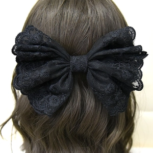 Vue détaillée du grand nœud en dentelle noire avec broderie florale sur les cheveux