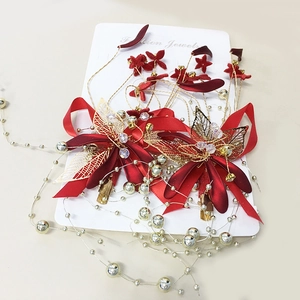 Detail von roten Satinschleifen-Haarclips mit goldenen Metallblättern und Perlenketten