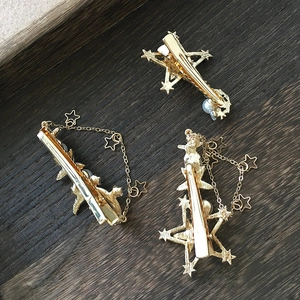 Detailaufnahme goldener Braut-Haarnadeln mit Perlen und Sternen auf dunklem Holz