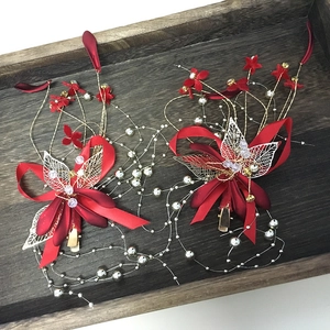 Detail von handgefertigtem Brauthaarschmuck mit roten Seidenblüten und goldenen Blättern