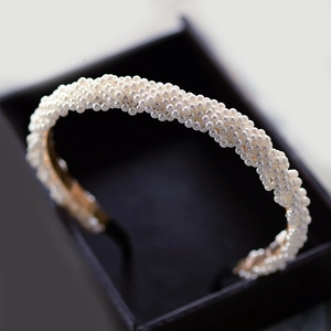 Close-up of a densely beaded white pearl headband in a black gift box