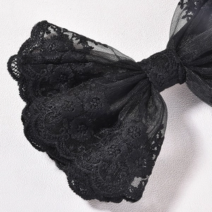 Détail d'un nœud papillon en dentelle noire avec broderie florale et bords festonnés
