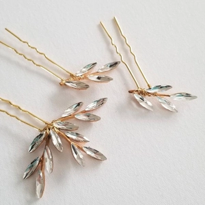 Close-up of three handmade bridal hair pins with gold alloy leaves and marquise rhinestones