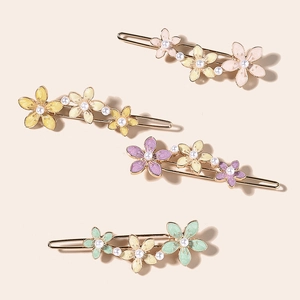 Detailed close-up of four floral hair clips with colorful enamel petals and pearls