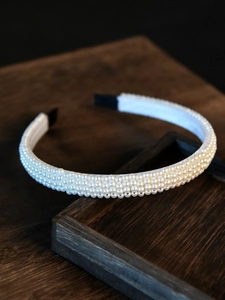Macro shot of elegant white faux pearls on headpiece with three rows and soft luster