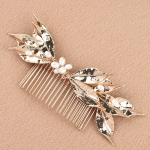 Close-up of golden leaf hair comb with handcrafted pearls and detailed metal vein textures