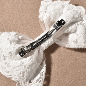 Détail de la pince à ressort en métal sur un nœud de mariée en dentelle blanche gravé