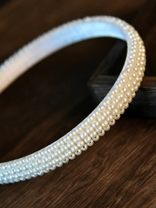 Detailed macro view of triple-row white faux pearls on an elegant bridal headband