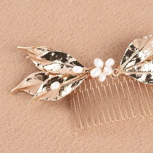 Macro detail of bridal hair comb with golden alloy leaves and handmade pearls