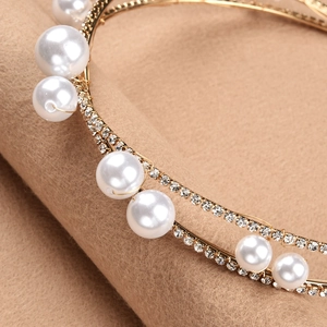 Macro detail of bridal headband featuring layered pearls and sparkling rhinestones on gold metal