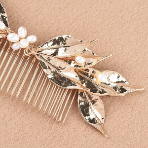 Detailed close-up of bridal hair comb featuring golden alloy leaves and white pearls
