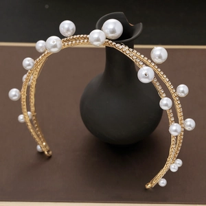Close-up of golden bridal headband with pearls and rhinestones on a dark display