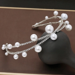 Detailed view of silver bridal headband with pearls and rhinestones on black display