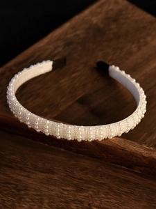 Detailed view of elegant white faux pearls on a headband with comfortable black ends
