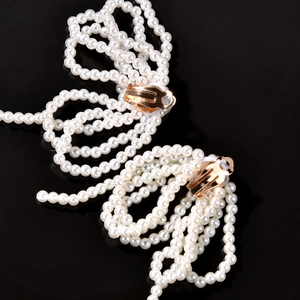 Macro di eleganti orecchini a clip da sposa con perle bianche e chiusura in metallo dorato