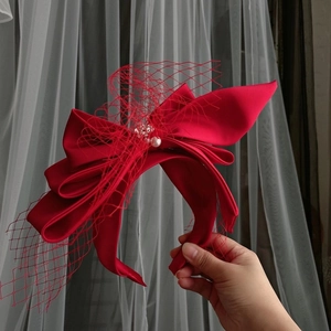 Detail of red satin bridal headband with mesh veil and pearl embellishments