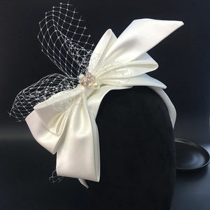 Detail of bridal headband with cream satin bow, pearl buckle and elegant mesh veil