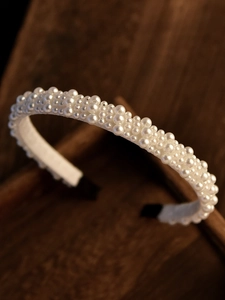 Macro shot of faux pearl bridal headband with white silk wrap and dense pearl inlay