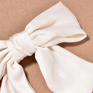 Detailed macro view of white pleated satin fabric and silk texture on the bow hair clip