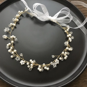 Detail of handmade pearl and crystal headband with white organza ribbon on black plate