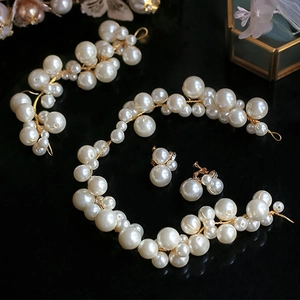 Elegant bridal pearl hair vine and earring set with gold wire on reflective black surface