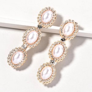 Close-up of golden hair clips featuring white oval pearls and sparkling rhinestones