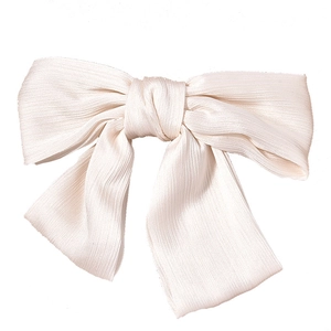 Close-up of pleated white chiffon wedding bow hair clip with elegant long ribbons