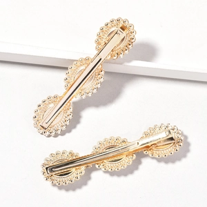 Detailed view of two gold alloy hair clips with scalloped edges and pearl rhinestones