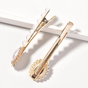 Close-up of golden alloy hairpins with white pearls and sparkling rhinestones