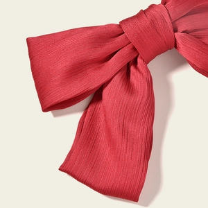 Close-up of red pleated fabric bow hair clip with vertical rib texture for weddings