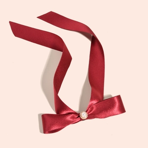 Detailed shot of dark red velvet bow with a large pearl center and gold metal rim