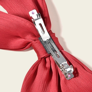 Close-up of the red pleated bow hair clip showing the silver spring metal clip
