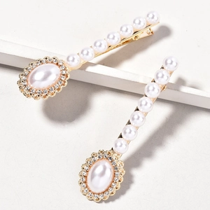 Detail view of elegant gold-toned hair clips featuring round pearls and sparkling rhinestones