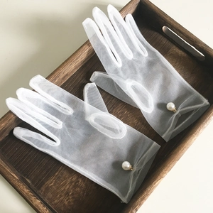 Elegant white sheer tulle bridal gloves with large pearl accent on wooden tray