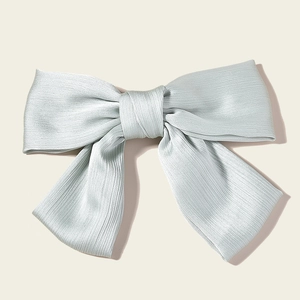 Macro view of light blue pleated satin bow hair clip with fine vertical textures