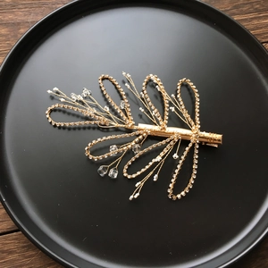 Detail of handmade gold bridal hair clip with pearls and sparkling crystals on black surface
