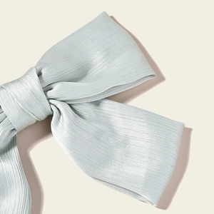 Close-up of light blue pleated ribbon hair bow showing detailed fabric texture and matte finish