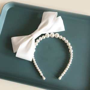Serre-tête de mariée avec grand nœud en satin et perles sur un plateau bleu