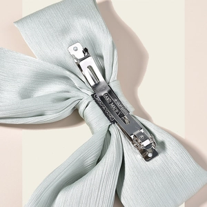 Close-up of handmade metal spring clip and pleated satin fabric on a bridal hair bow