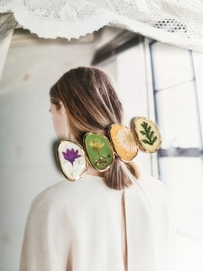 Détail de la pince à cheveux en résine avec de vraies fleurs séchées et cadre en métal doré