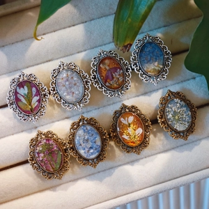 Handmade resin ring featuring real dried flower specimens in vintage lace alloy frames