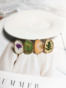 Détail macro d'une barrette en alliage doré avec de vraies fleurs séchées et perles