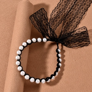Detail of vintage pearl lace necklace featuring elegant black bow and white pearls